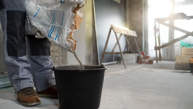 Mann blander betongblanding i bøtte