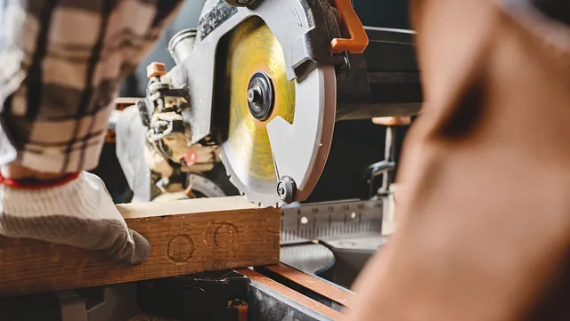 Snekker bruker kappsag for å kappe planke